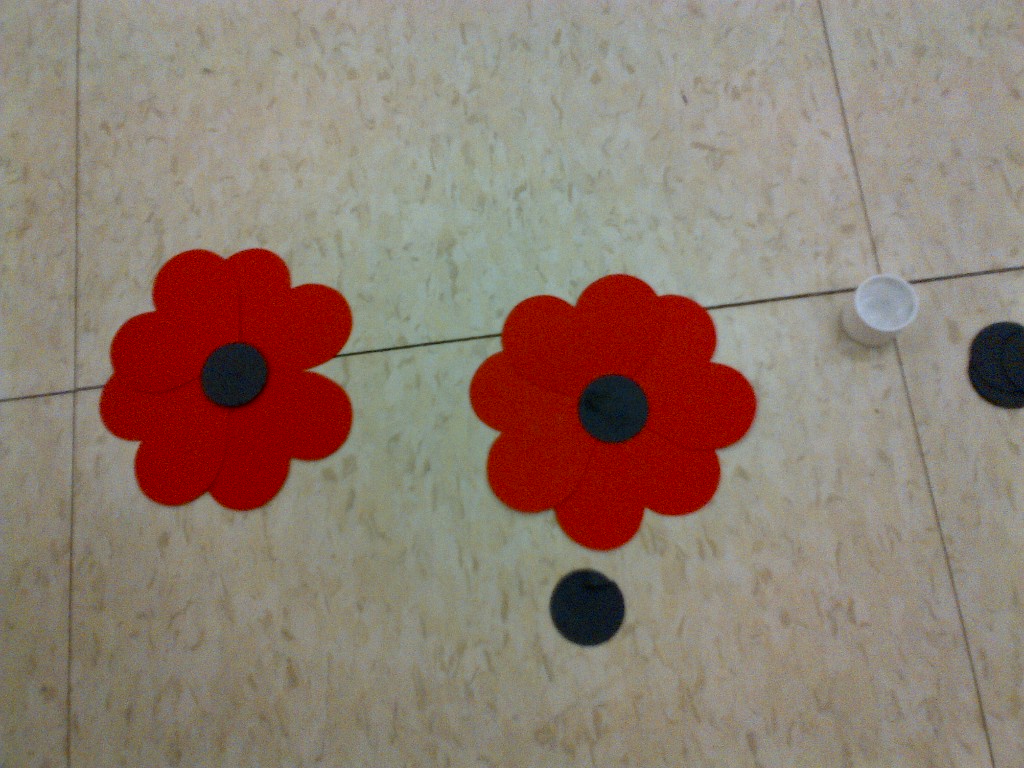 Two completed construction paper poppies lay on a gym floor