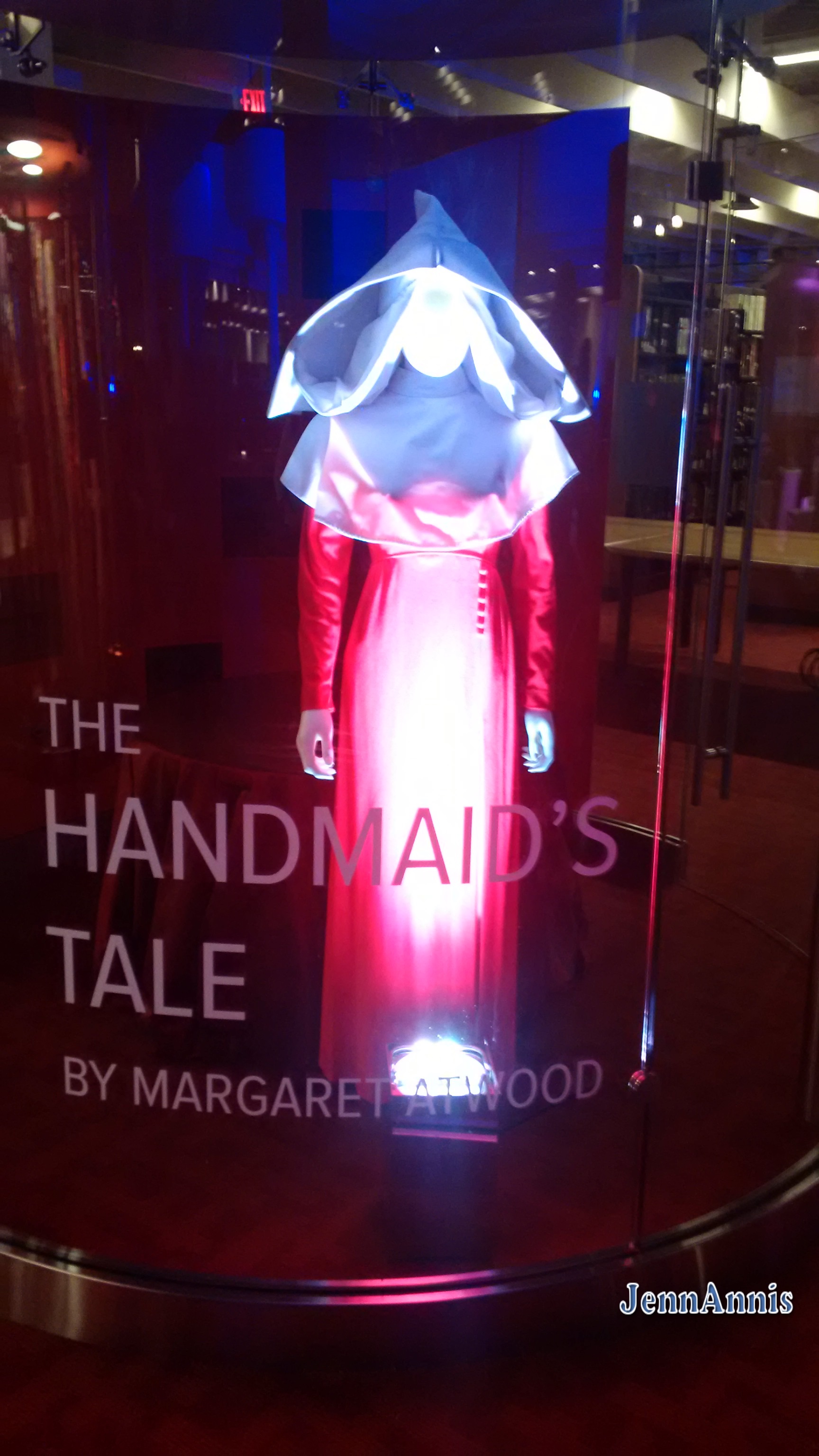 A mannequin dressed as a handmaiden in a red dress and white hood Text reading: The Handmaid's Tale