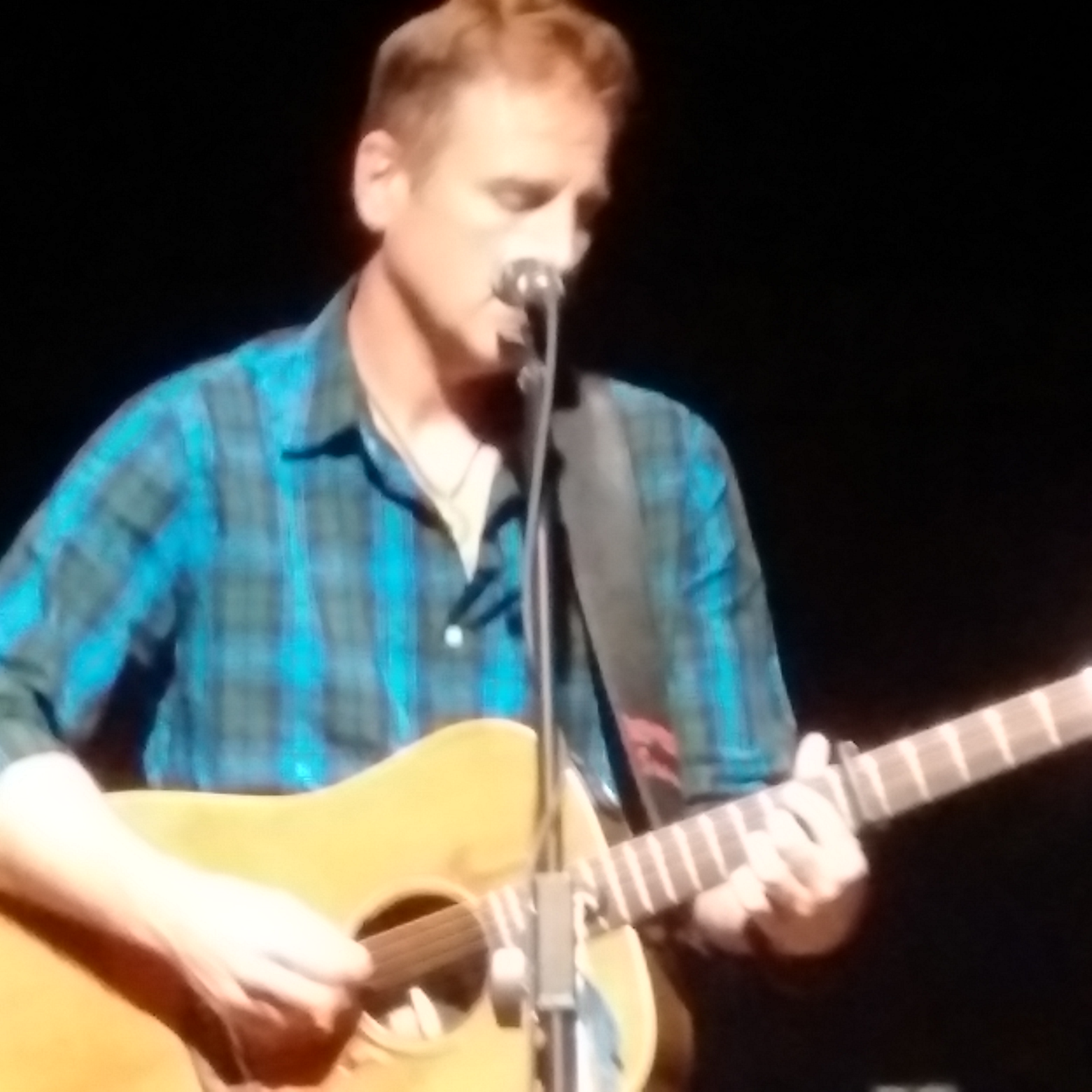 Sean McCann sings into a microphone on stage