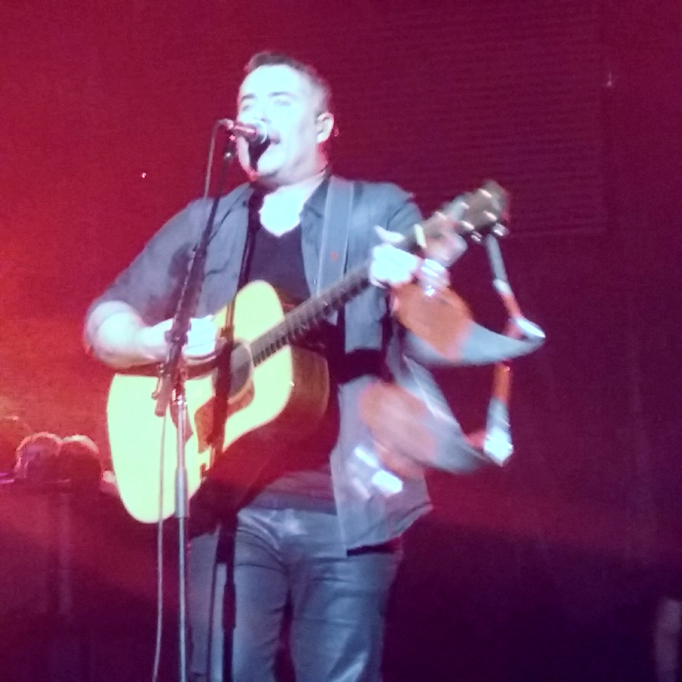 Ed Robertson sings into a microphone while a pair of underwear hangs off the neck of his guitar.