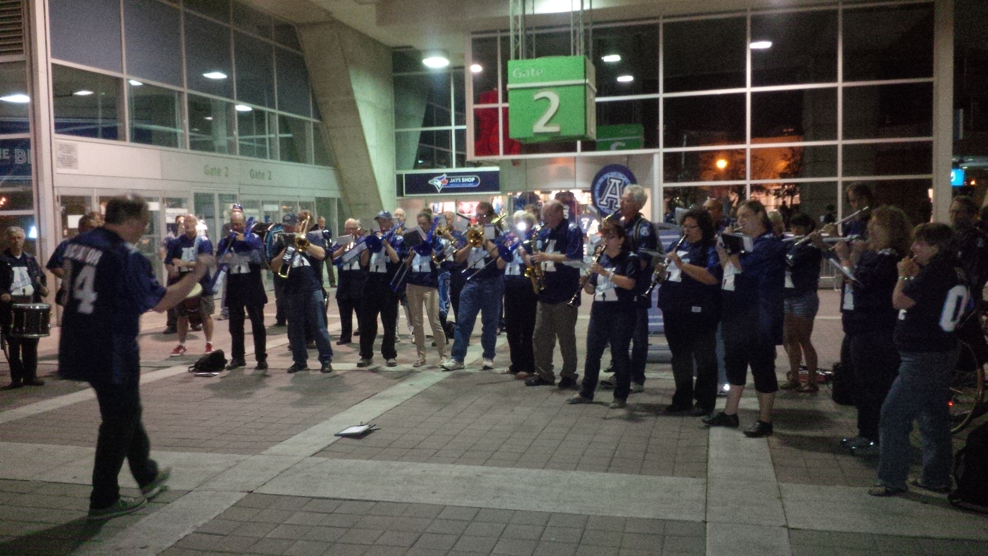 A marching band wearing Argonotes Jerseys plays outside the Skydome