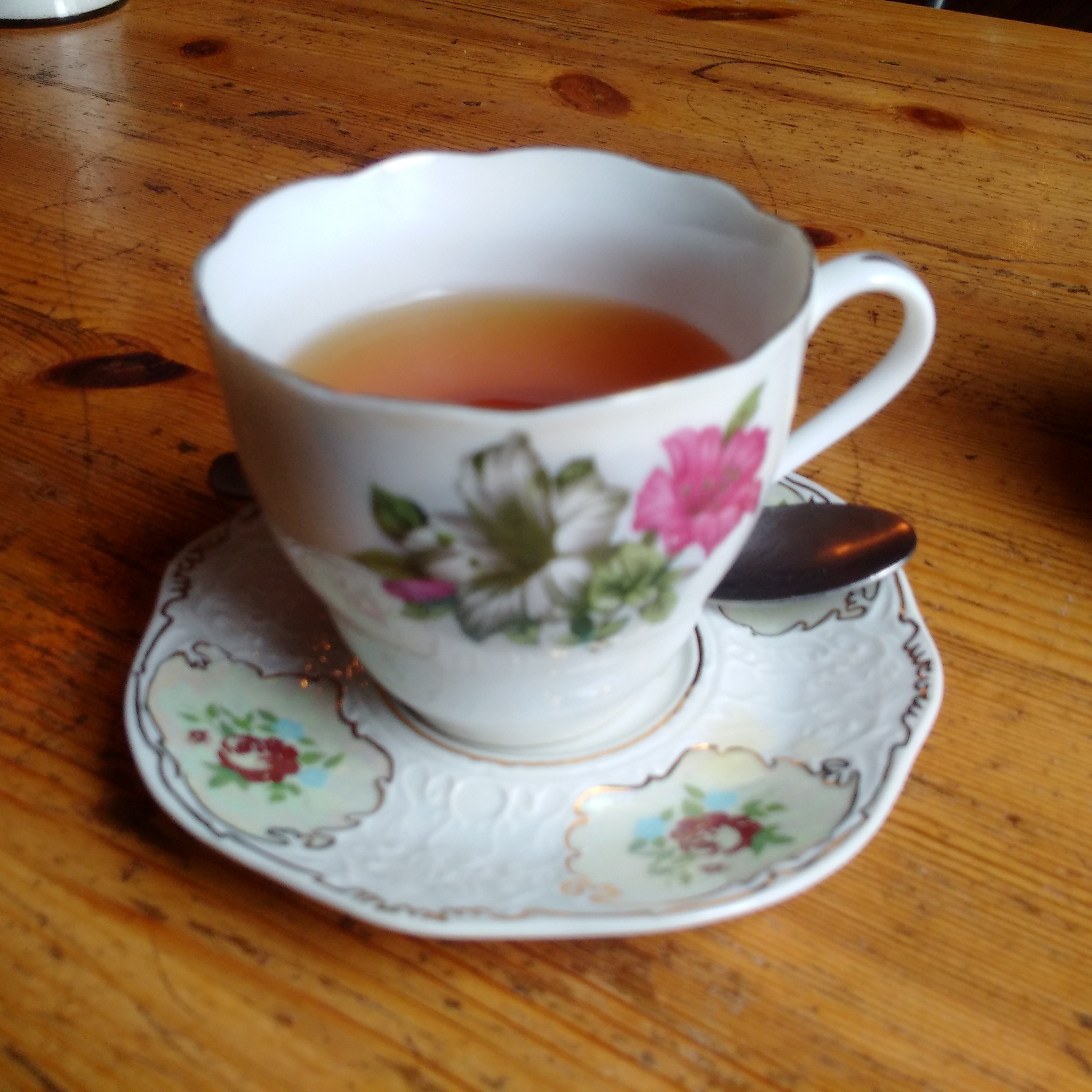 A small tea cup with flowers on it filled with green tea